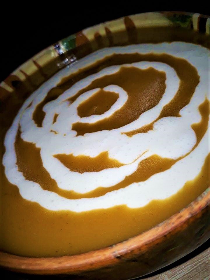 A bowl of sweet potato soup with a swirl of cream on top.