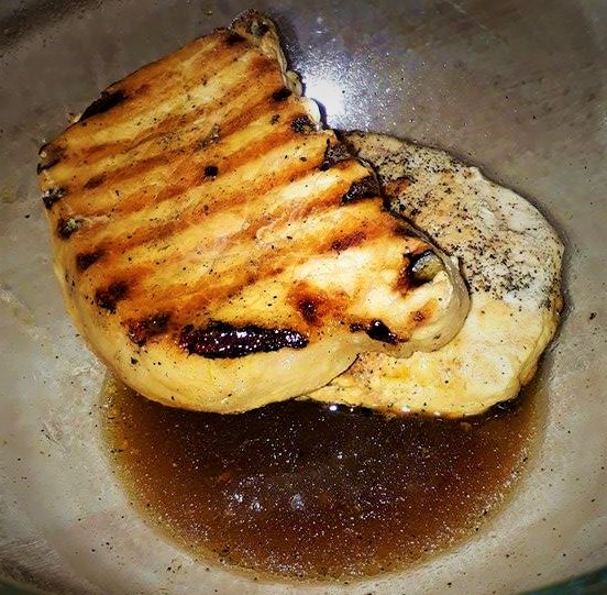 Grilled chicken breast in a bowl with sauce.