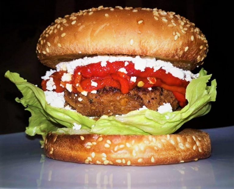 A burger with tomatoes, lettuce and cheese.