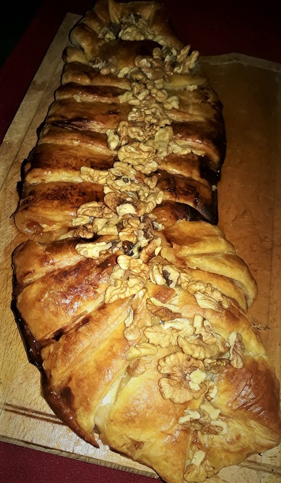 A pastry with nuts on top of a cutting board.